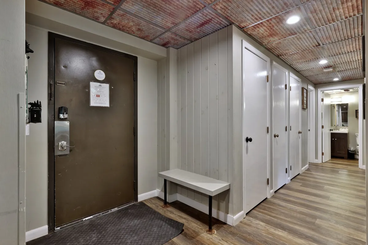 This image features the entrance door, a cozy bench, and storage closets, establishing a sense of arrival and transition from outside to inside. The welcoming scene hints at the property's accessibility and the beginning of a guest's journey, making it ideal for an 'explore'-themed section emphasizing practical perks and ease of access.