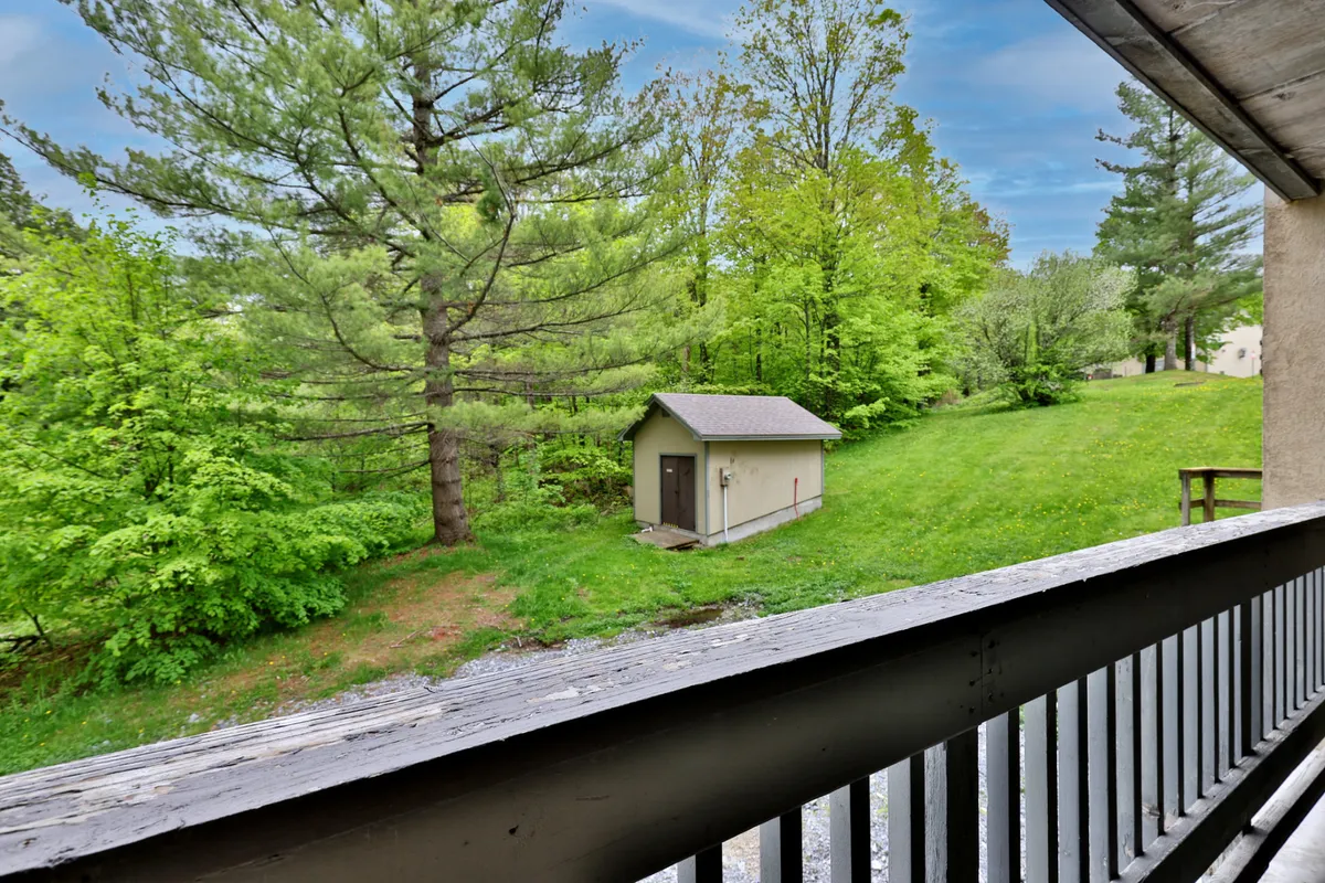 A tranquil outdoor perspective featuring a balcony overlooking greenery, distant trees, and a peaceful storage shed. The natural setting invites guests to relax, watch wildlife, or marvel at sunrise views, emphasizing the connection to the surrounding landscape.