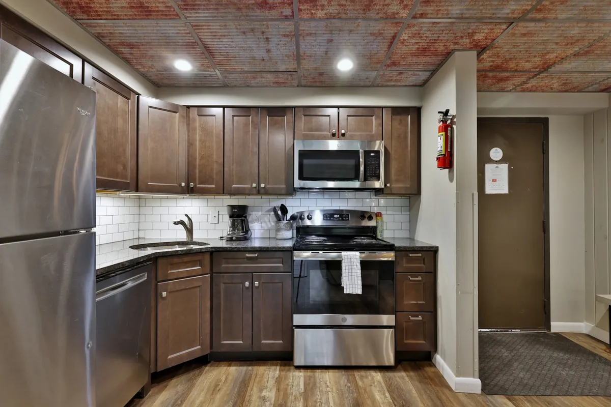 A modern kitchen with stainless steel appliances, granite countertops, and wood cabinetry, designed for group cooking and entertaining. The layout is open and welcoming, ideal for prepping meals and spending time with loved ones.