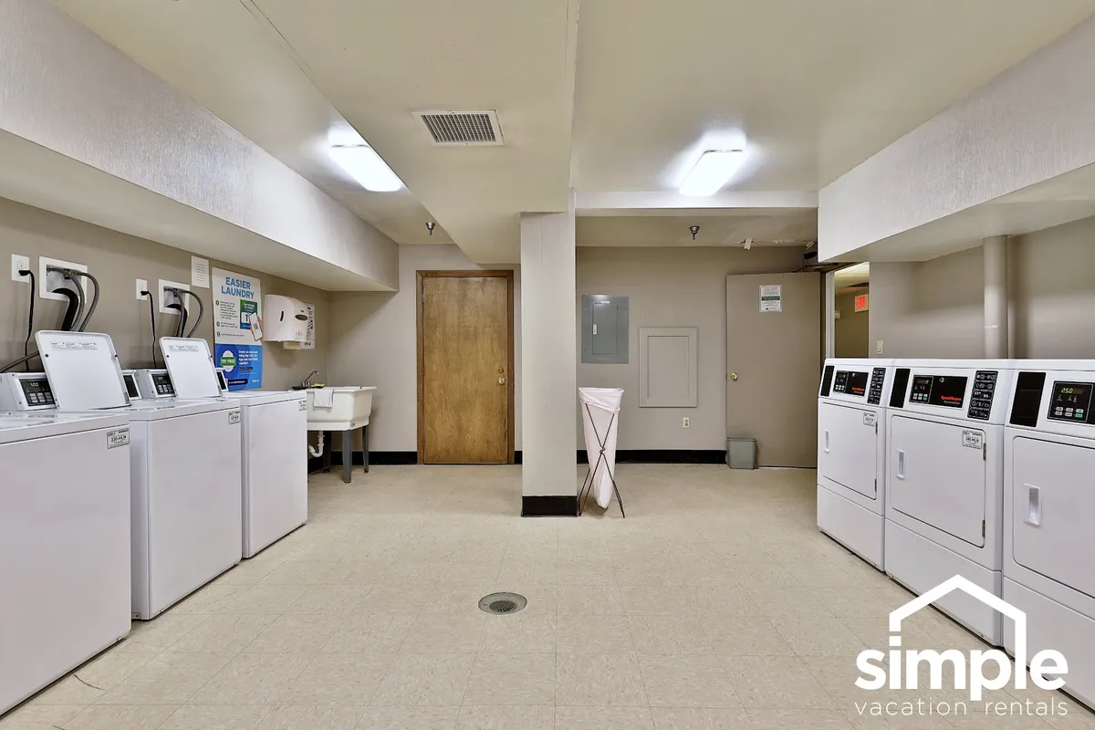 A practical, straightforward laundry room with washing machines, dryers, and a utility sink, subtly showcasing the self-catering and cost-saving features available to guests. The space is clean, functional, and hints at the ability to manage extended stays affordably.