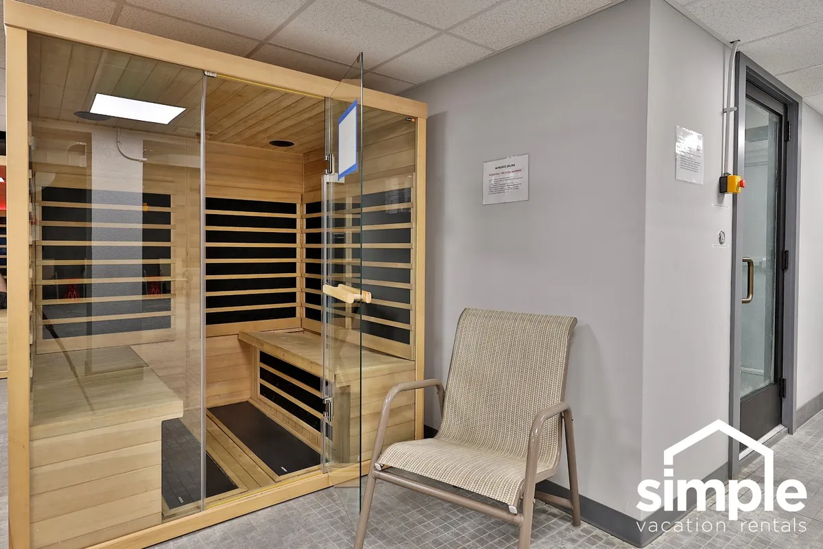 A tranquil sauna room with wooden benches and a single chair, softly lit to emphasize warmth and relaxation. The intimate space suggests a place for unwinding after a long day outdoors or sharing quiet conversation.