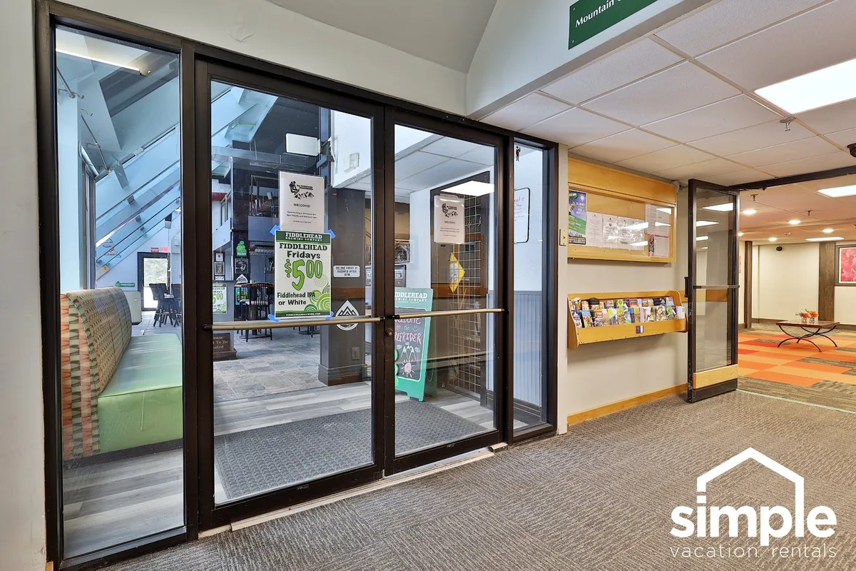 A modern entrance area with glass doors, clear informational signage, a reception zone, and a comfortable seating area where guests can gather, wait, or get local tips.